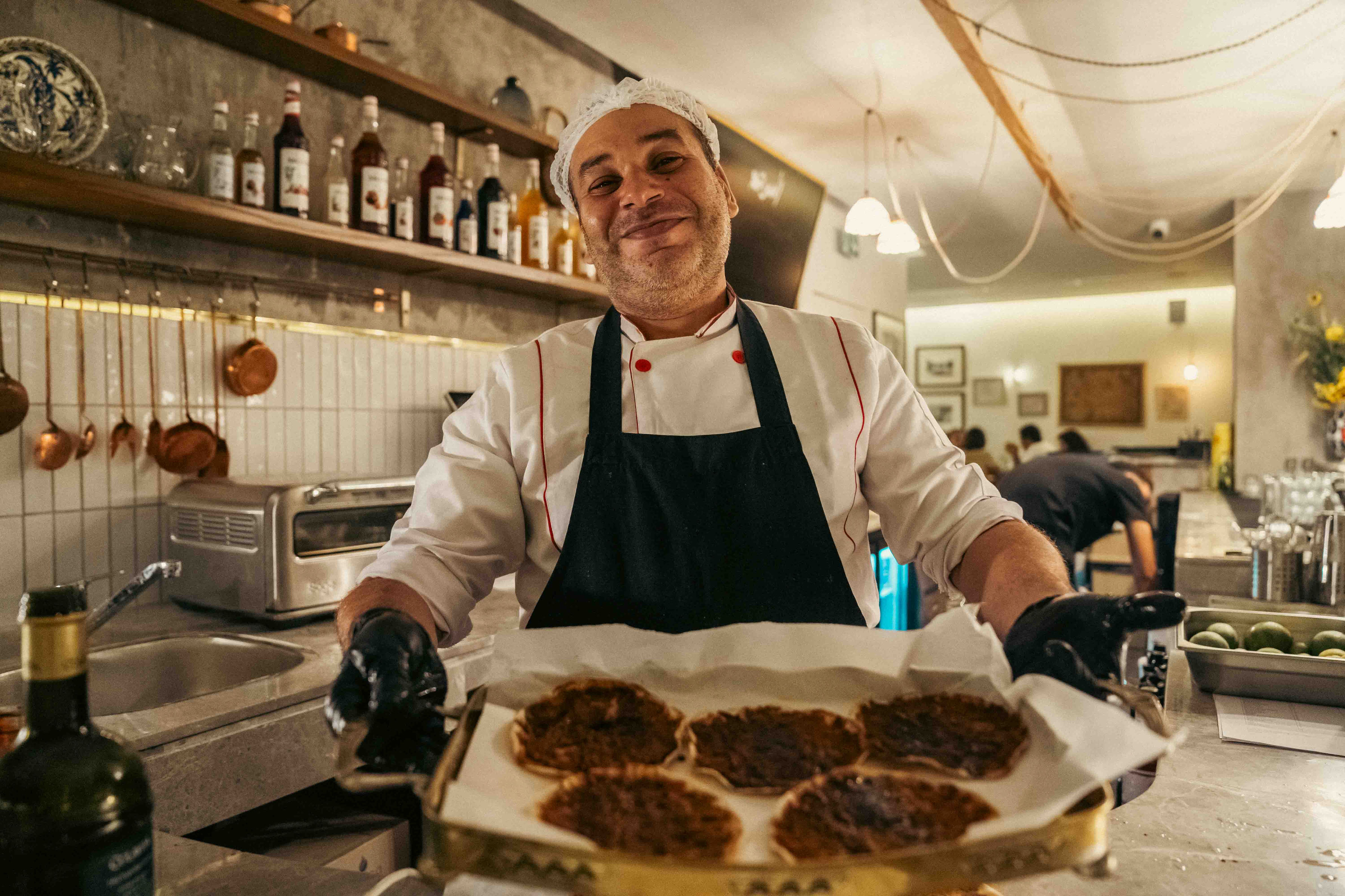 A smiling Almería chef presenting a tray of freshly baked flatbreads in the kitchen