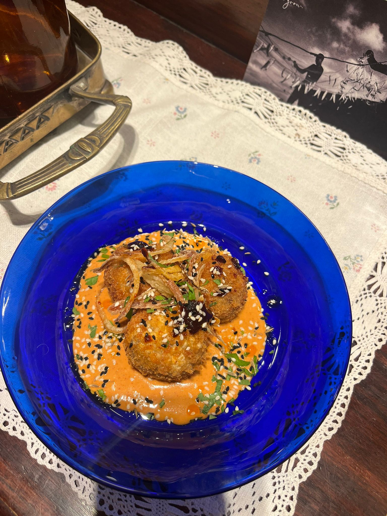 Golden croquettes over a smoky red pepper sauce on a cobalt plate