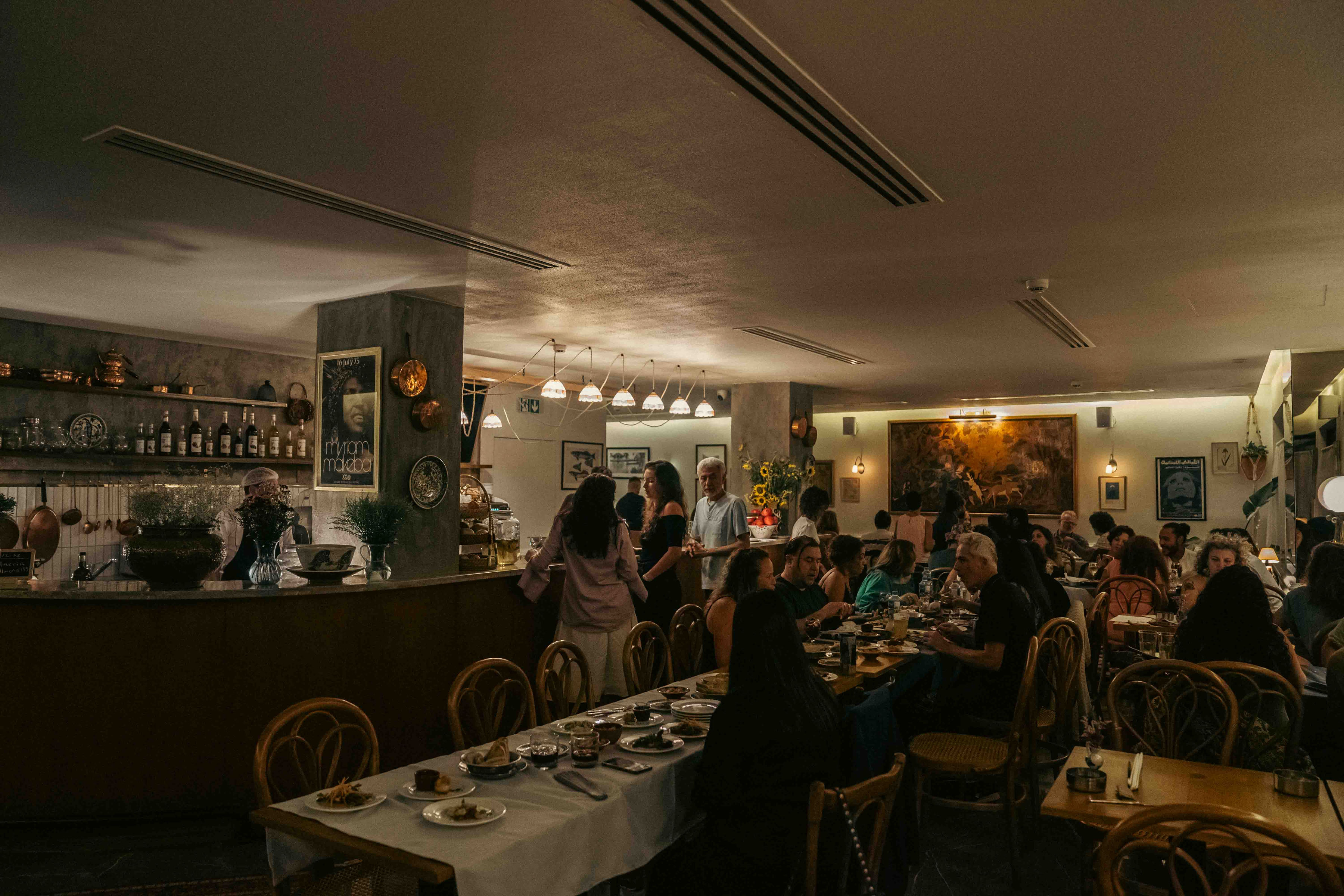 The warm, candlelit dining room at Almería filled with guests sharing plates