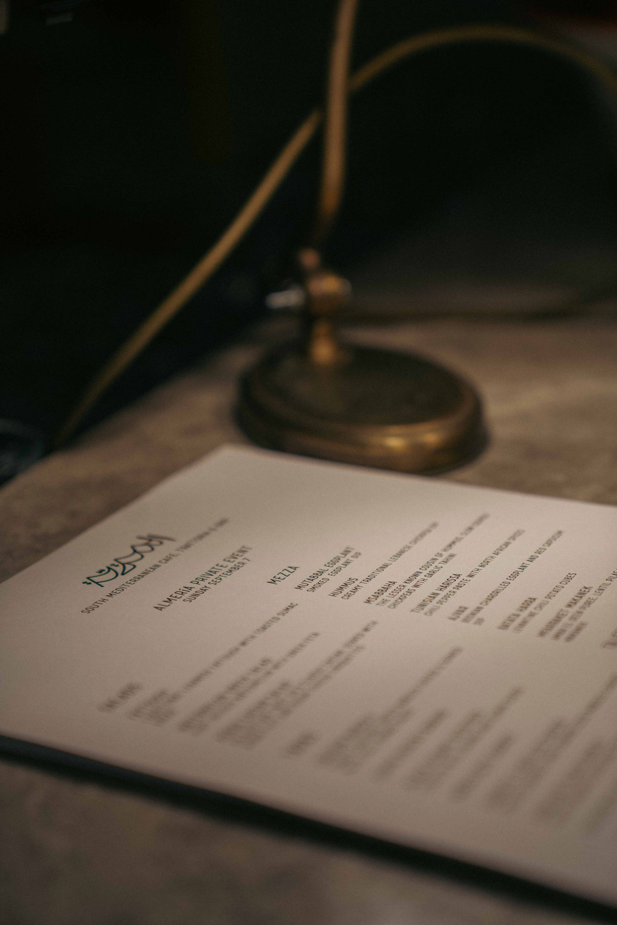 An Almería private-event menu resting beneath a brass lamp